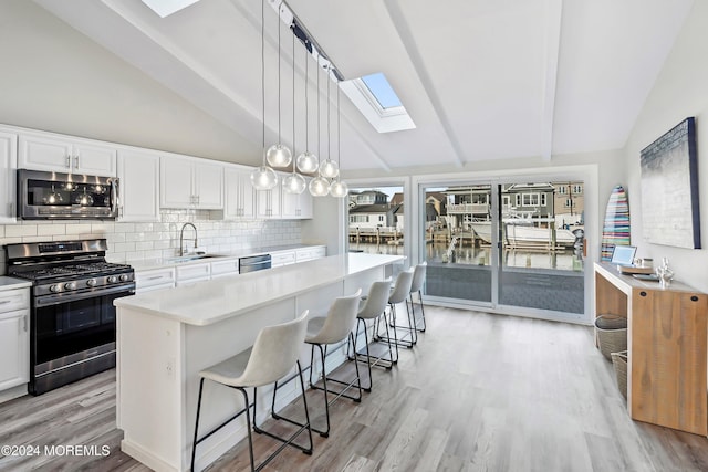 kitchen with a kitchen island, appliances with stainless steel finishes, white cabinetry, sink, and a kitchen breakfast bar