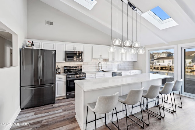 kitchen featuring sink, a breakfast bar area, appliances with stainless steel finishes, white cabinetry, and a center island