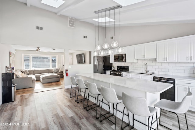 kitchen featuring white cabinetry, sink, a breakfast bar area, and black appliances