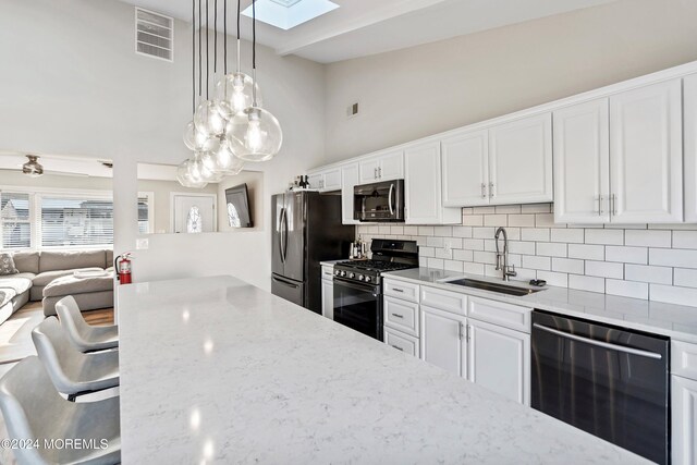 kitchen featuring white cabinetry, sink, decorative light fixtures, and appliances with stainless steel finishes