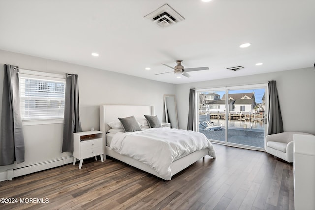 bedroom featuring multiple windows, a baseboard heating unit, access to outside, and dark wood-type flooring