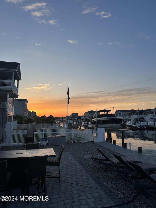 patio terrace at dusk with a dock and a water view