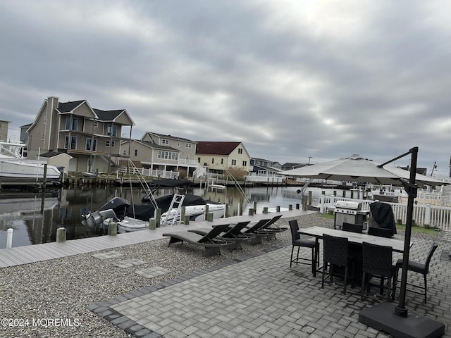 view of patio with a water view and a dock