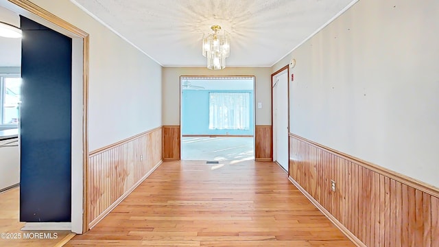 hallway with light hardwood / wood-style flooring, plenty of natural light, and ornamental molding