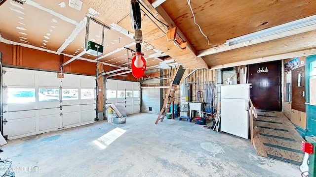 garage featuring sink, a garage door opener, gas water heater, and white refrigerator