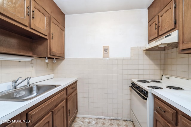 kitchen with electric stove, sink, and tile walls