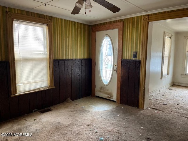 foyer featuring ornamental molding, visible vents, carpet floors, and a ceiling fan