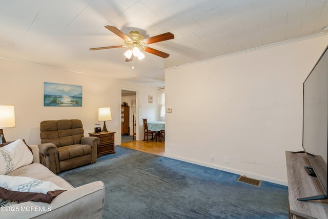 living room with ceiling fan, ornamental molding, and carpet