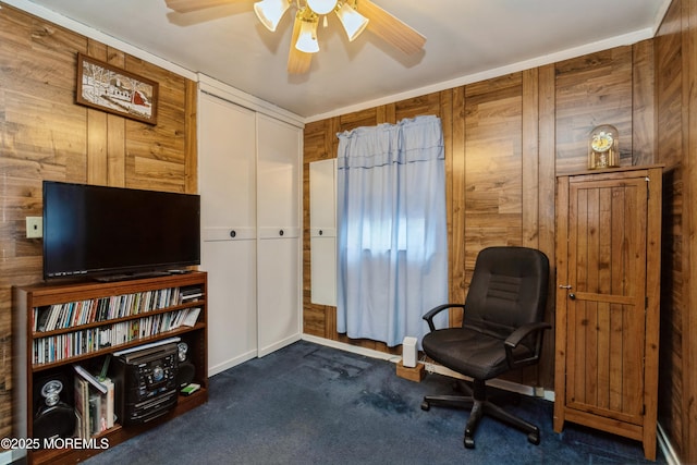 sitting room featuring dark colored carpet, ceiling fan, and wood walls