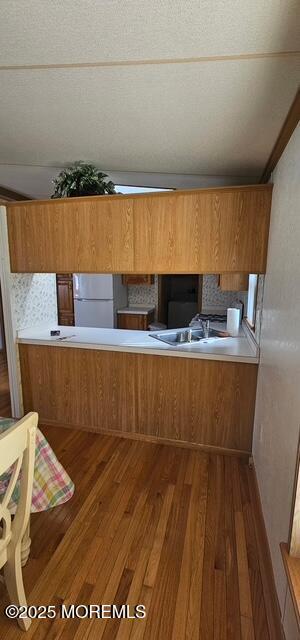 kitchen featuring white refrigerator, dark wood-type flooring, sink, and kitchen peninsula