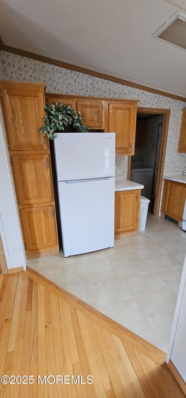 kitchen with washer / dryer, ornamental molding, white fridge, and lofted ceiling