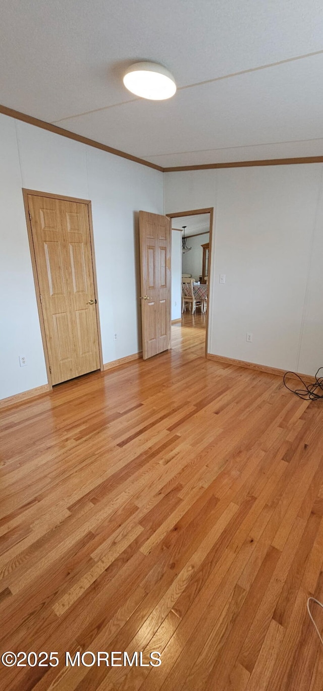 empty room with ornamental molding and light wood-type flooring