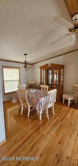 dining area with crown molding, lofted ceiling, and light hardwood / wood-style flooring