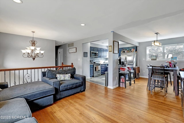 living room with baseboards, visible vents, light wood-type flooring, a notable chandelier, and recessed lighting