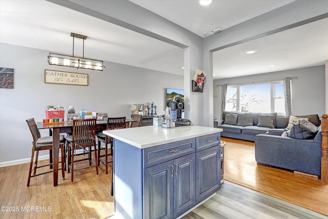 kitchen with open floor plan, light countertops, a center island, light wood finished floors, and decorative light fixtures