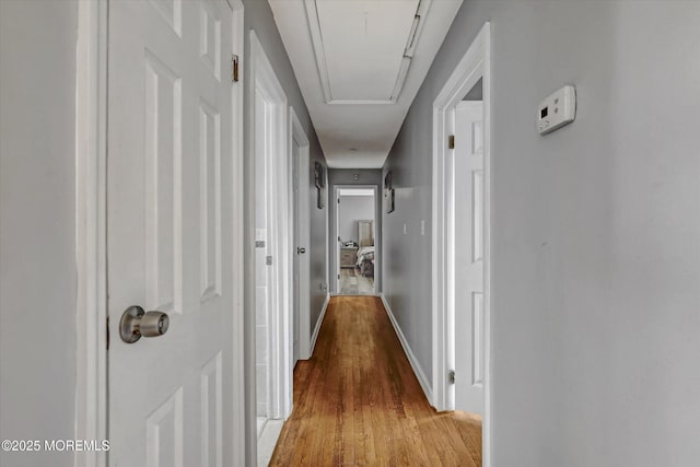 corridor with attic access and light wood-style flooring