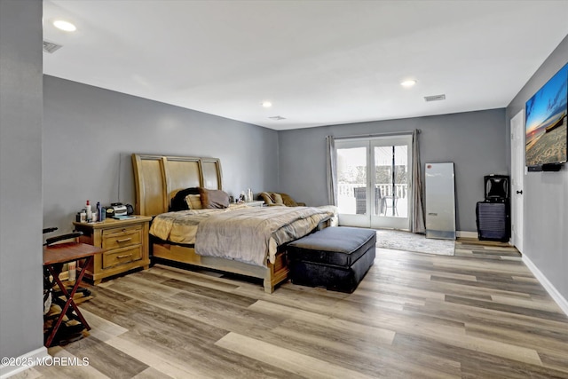 bedroom with baseboards, visible vents, and wood finished floors