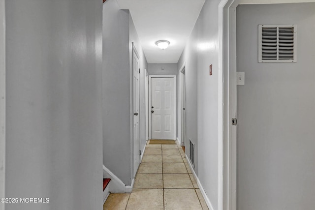 hallway with visible vents, baseboards, and light tile patterned floors