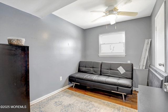 living area featuring a ceiling fan, light wood-type flooring, and baseboards