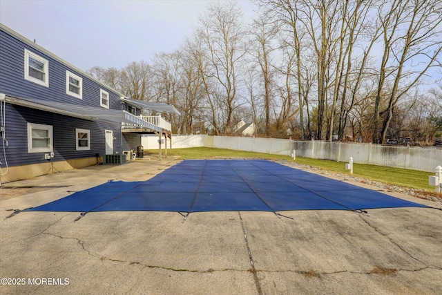 view of swimming pool with cooling unit, a patio area, a lawn, and a fenced backyard