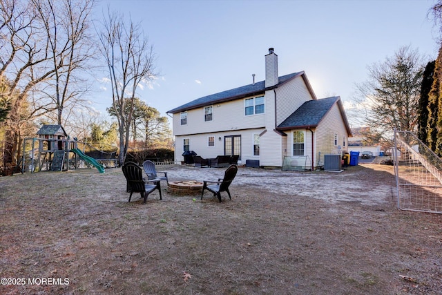 back of property with a playground, central AC, and a fire pit