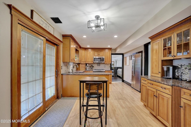 kitchen featuring appliances with stainless steel finishes, sink, a breakfast bar area, and dark stone counters