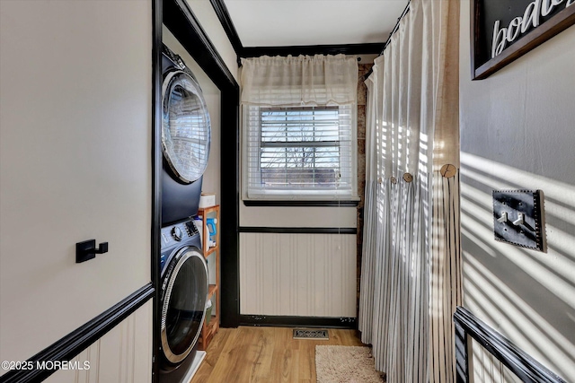 laundry room featuring stacked washer and dryer and light wood-type flooring