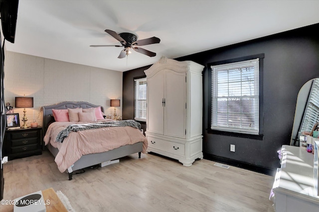 bedroom featuring ceiling fan, light hardwood / wood-style floors, and multiple windows