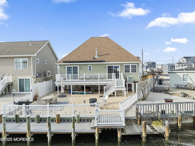 back of house with a deck with water view and a patio