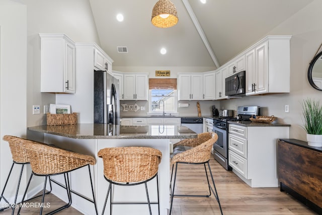 kitchen with white cabinetry, a breakfast bar, kitchen peninsula, and appliances with stainless steel finishes