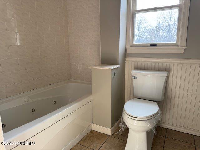 bathroom featuring tile patterned flooring, a bath, and toilet