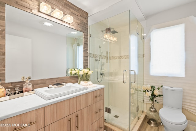 bathroom with a shower with door, vanity, and toilet