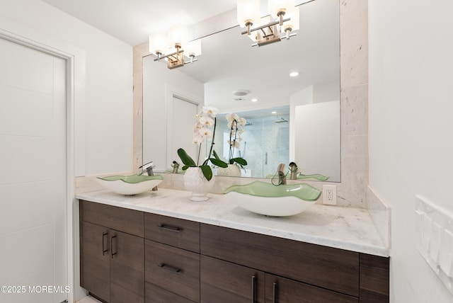 bathroom with vanity, an inviting chandelier, and a shower with shower door