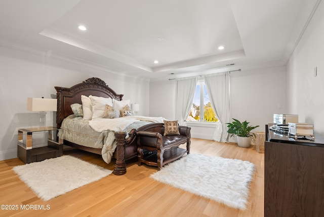 bedroom with a raised ceiling and light hardwood / wood-style flooring