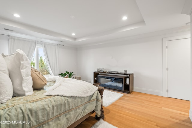 bedroom featuring hardwood / wood-style floors and a tray ceiling