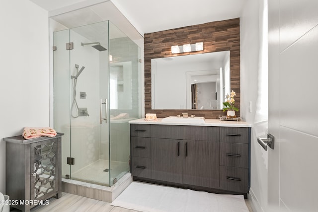 bathroom with vanity, backsplash, and a shower with door