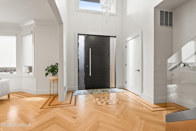 foyer with parquet flooring and a towering ceiling