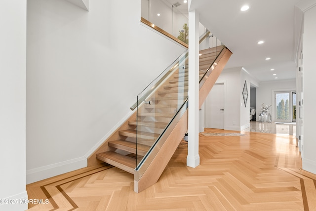 staircase with crown molding and parquet floors