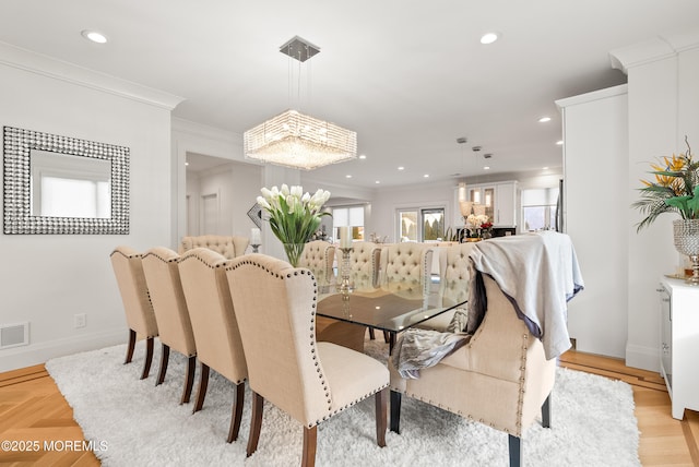 dining area with crown molding and light parquet flooring