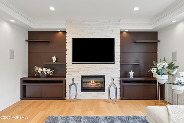 living room featuring crown molding, a fireplace, and hardwood / wood-style floors