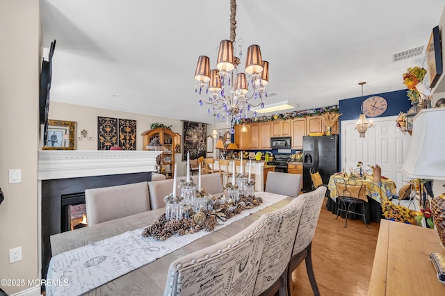 93 Golden Eye Ln, Port Monmouth, NJ 07758 - dining space featuring a chandelier, light wood-style floors, visible vents, and a lit fireplace