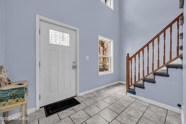 tiled foyer featuring a towering ceiling and plenty of natural light