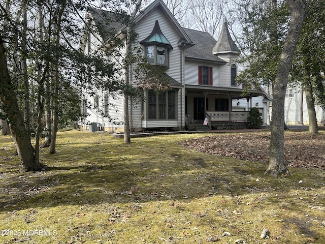 victorian house featuring central AC unit, a front yard, and covered porch