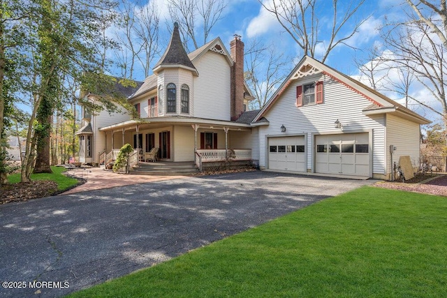 victorian home with a garage, a front yard, and covered porch