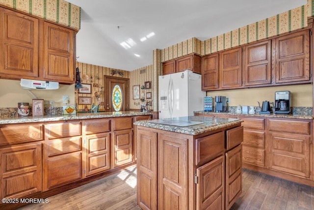 kitchen featuring vaulted ceiling, dark hardwood / wood-style flooring, a center island, white fridge with ice dispenser, and light stone countertops