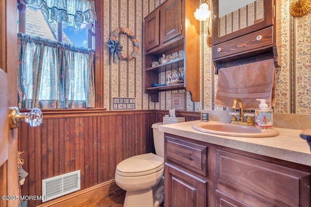 bathroom with vanity, wood-type flooring, wooden walls, and toilet