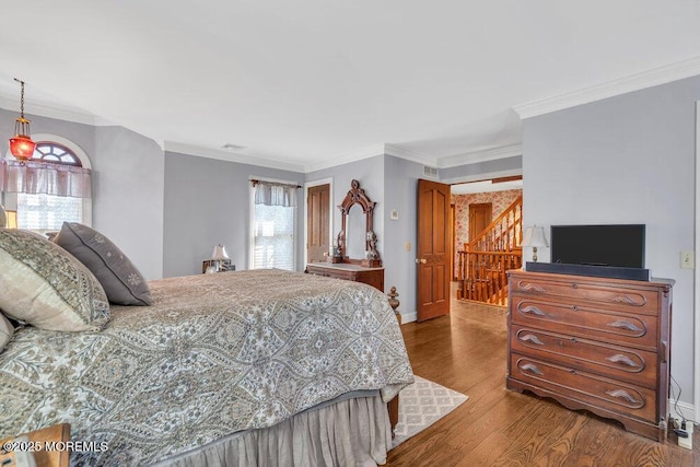 bedroom with ornamental molding, wood-type flooring, and multiple windows