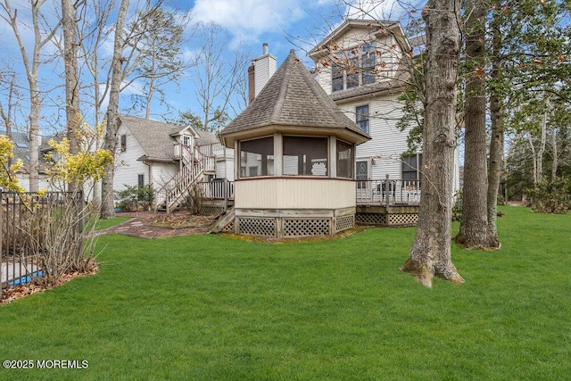 rear view of house with a wooden deck, a sunroom, and a lawn