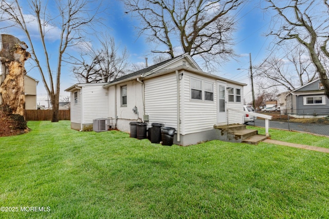 rear view of property with a lawn and central air condition unit