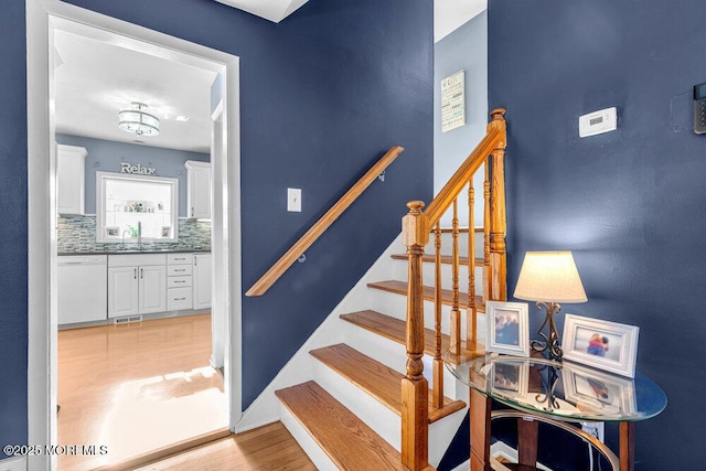 stairs featuring sink and hardwood / wood-style floors